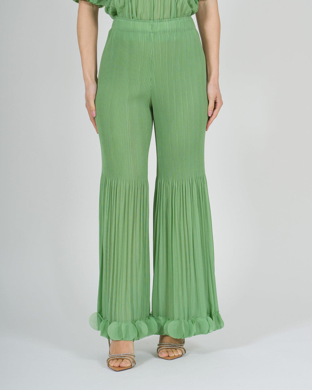 Pantalone amosa verde plissé con petali sul fondo 