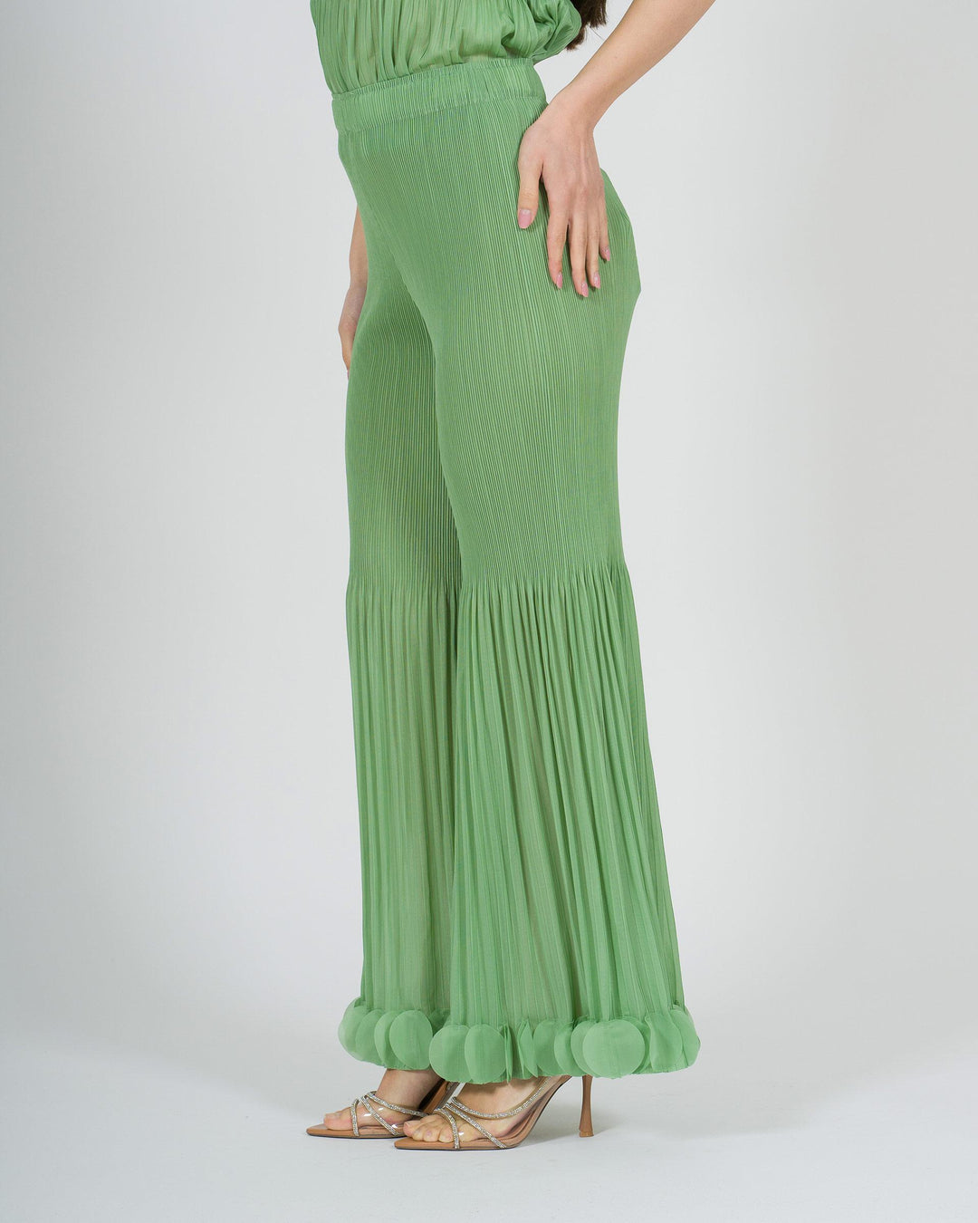 Pantalone amosa verde plissé con petali sul fondo 