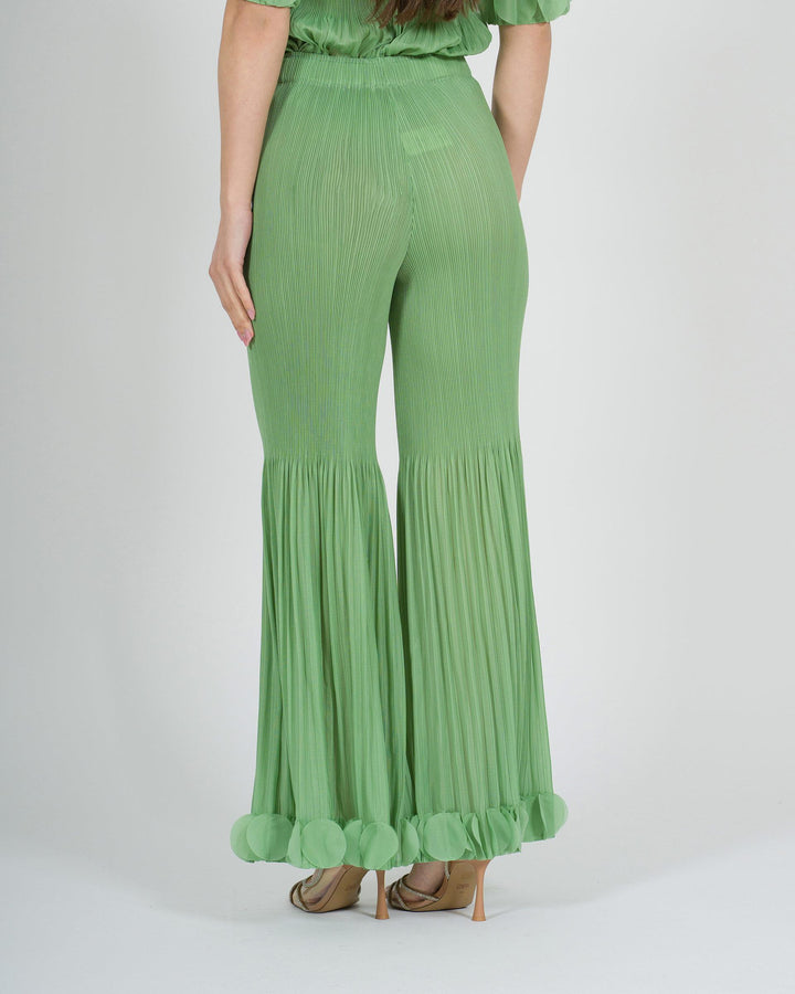 Pantalone amosa verde plissé con petali sul fondo 